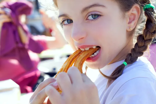 Ojos azules niña comiendo churros sonriendo — Foto de Stock
