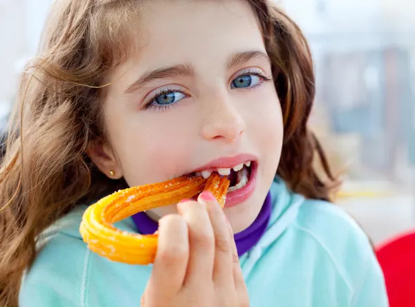 Blaue Augen kleines Mädchen, das Churros frittierte Crullers isst — Stockfoto