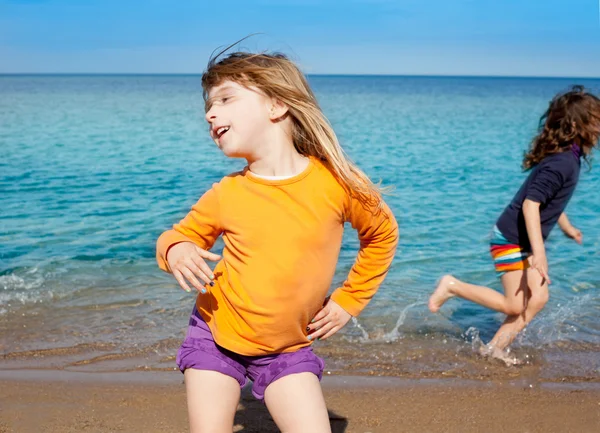Blond liten flicka dansa på stranden och vän kör — Stockfoto