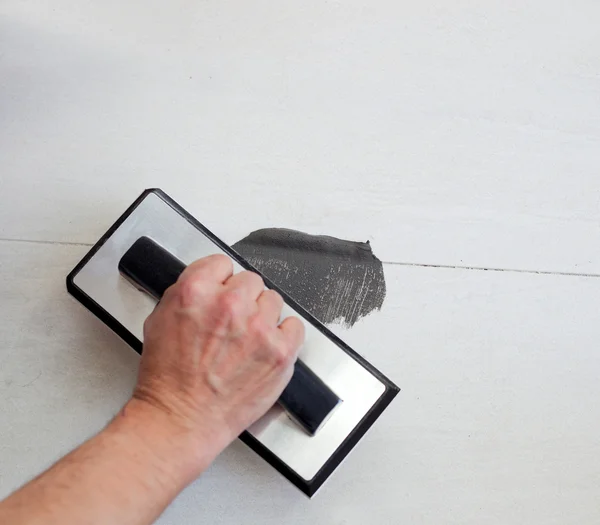 Grouting tiles with rubber trowel man hand — Stock Photo, Image