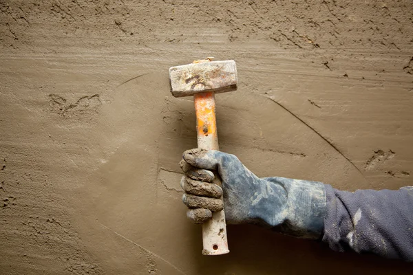 Martillo hombre con guantes en el fondo de cemento grunge — Foto de Stock