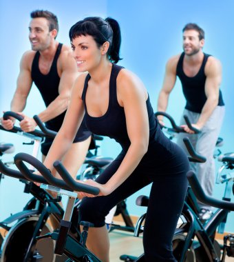 Stationary spinning bicycles fitness girl in a gym clipart