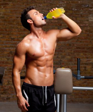 Muscle man at gym relaxed with energy drink clipart