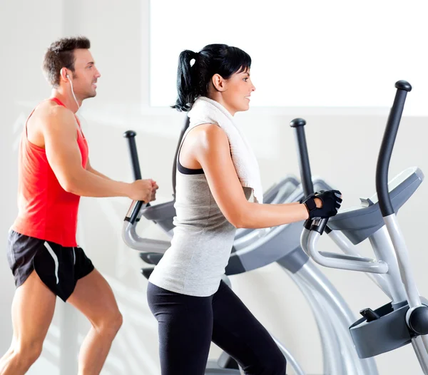 Mann und Frau mit Crosstrainer im Fitnessstudio — Stockfoto