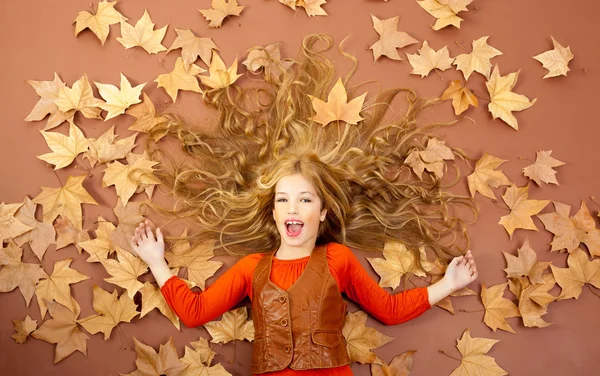 Осенью маленькая блондинка на сухих листьях деревьев — стоковое фото