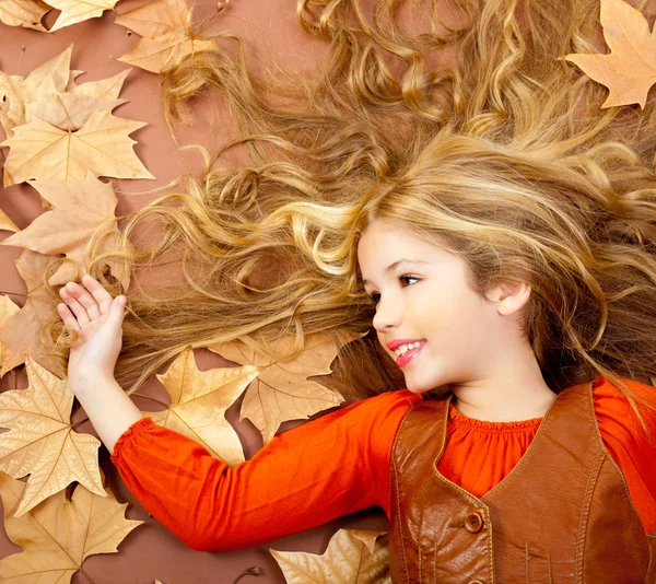 Herfst val beetje blond meisje op gedroogde boom bladeren — Stockfoto