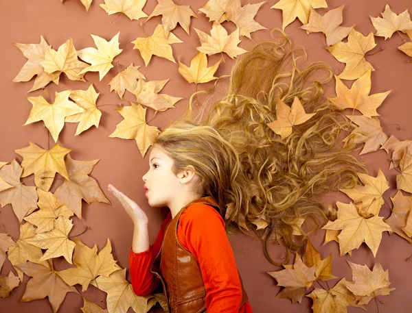 Осенняя девушка на сухих листьях, дующая губами ветра — стоковое фото