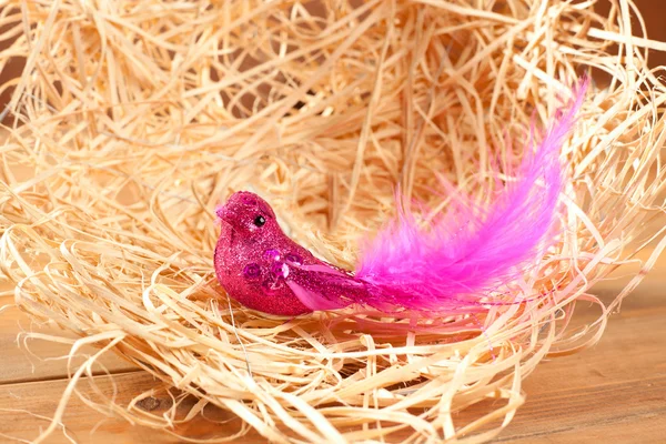 Fågel i halm boet med rosa fjädrar och glitter — Stockfoto