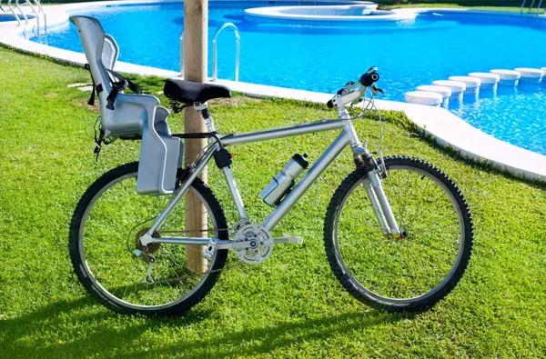 Bicicleta con asiento de bebé en la piscina de hierba al aire libre —  Fotos de Stock