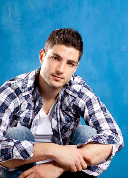 Jovem bonito com camisa xadrez em azul — Fotografia de Stock