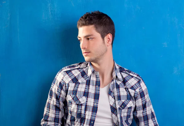 Jovem bonito com camisa xadrez em azul — Fotografia de Stock