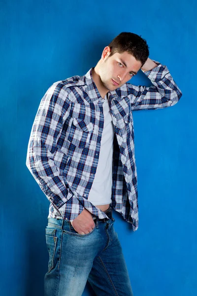 Bonito jovem com camisa xadrez jeans jeans jeans em azul — Fotografia de Stock