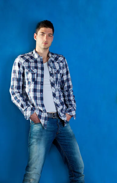 Όμορφος νεαρός άνδρας με καρό πουκάμισο τζιν τζιν στο μπλε — Φωτογραφία Αρχείου