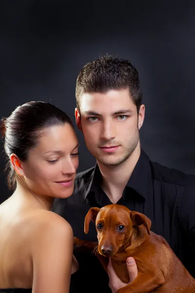 Casal apaixonado por um cachorrinho de estimação castanho — Fotografia de Stock