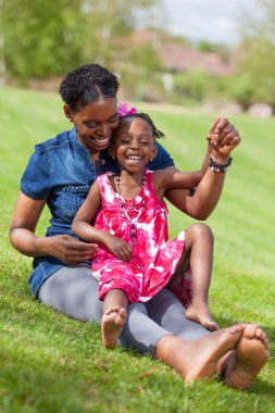 Adorable african mother with her daughter in the garden clipart