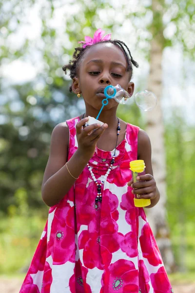 Cute african american little girl blowing soap bubbles — Stock Photo, Image