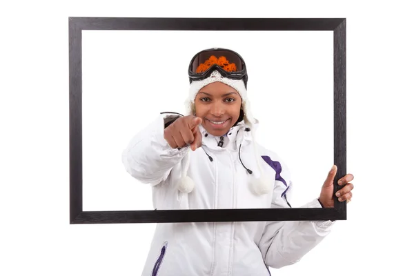 Young smiley woman in ski gears holding a picture frame — Stock Photo, Image