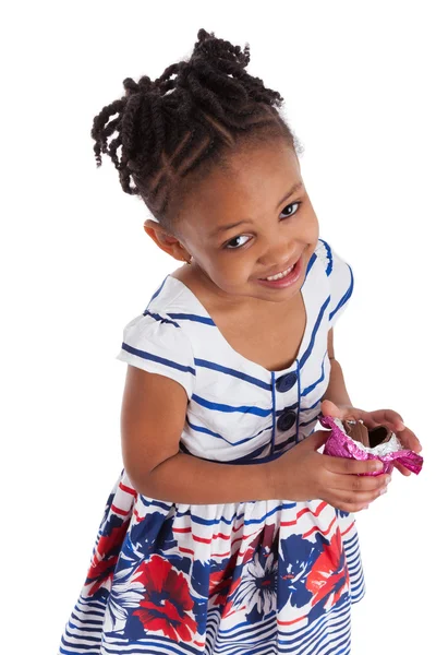 Маленькая африканская американка ест шоколадное пасхальное яйцо — стоковое фото