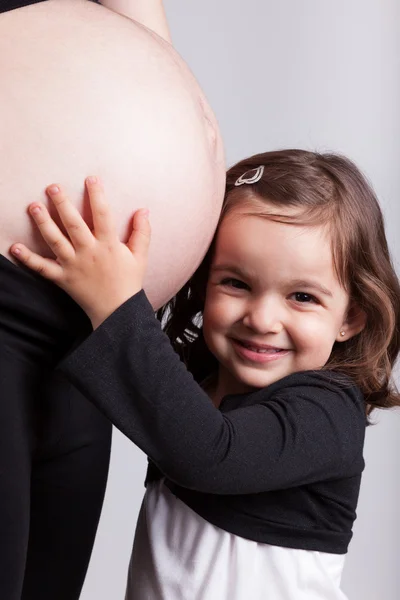 Gelukkig dochter omarmen haar zwangere moeder buik — Stockfoto