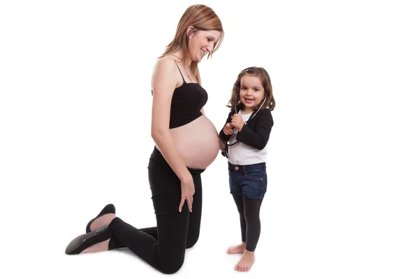 Menina examinando sua mãe grávida com um estetoscópio — Fotografia de Stock