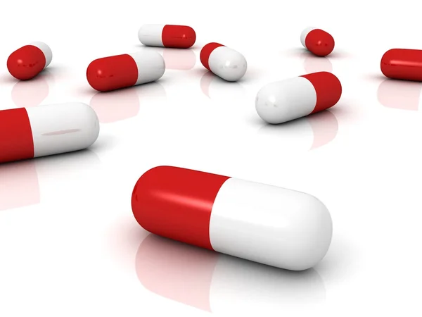 Red pharmaceutical capsules pills on white surface — Stock Photo, Image