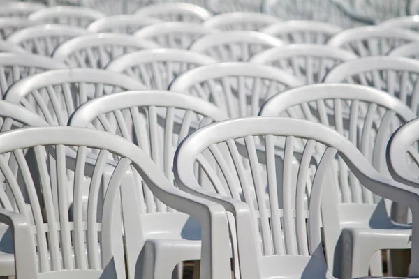 stock image Aligned white plastic chairs