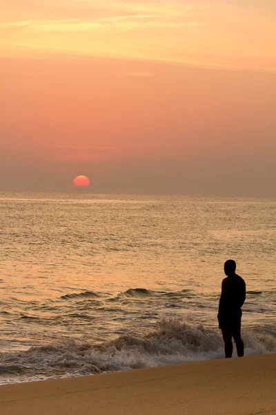 Man watches red sun at sunset — Stock Photo, Image