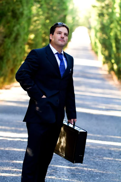 Homem de negócios com mala em uma estrada — Fotografia de Stock