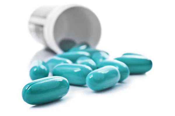 Синие таблетки пузырек с таблетками на белом фоне — стоковое фото