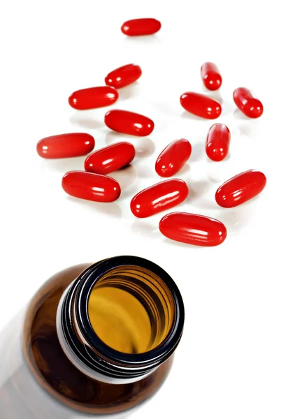 Pílulas vermelhas e garrafa pílula em branco — Fotografia de Stock