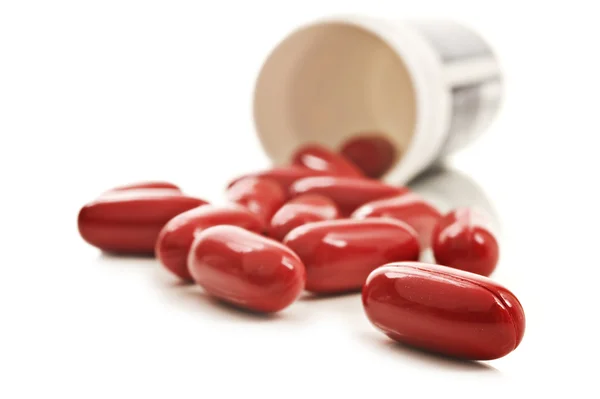 Червоні таблетки пляшка таблеток на білому тлі Стокове Фото