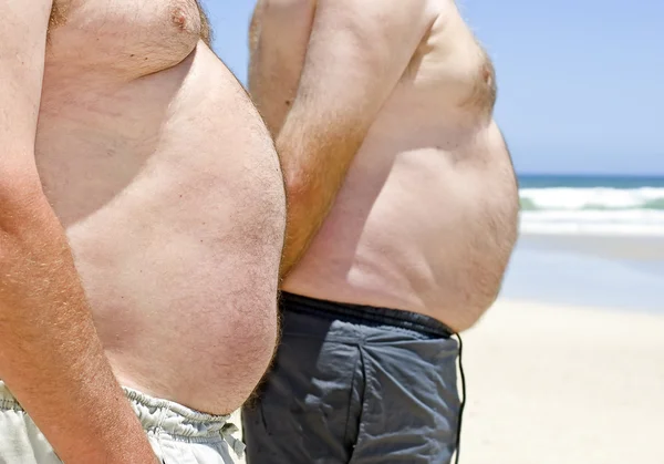 Närbild på två feta fett män på stranden — Stockfoto