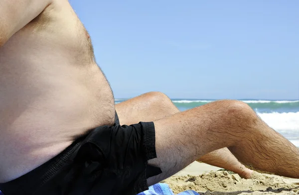 Niezdrowy tłuszcz człowiek siedzi na plaży — Zdjęcie stockowe