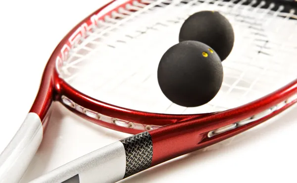 Close up of a red and silver squash racket and ball on a white background with space for text — Stock Photo, Image