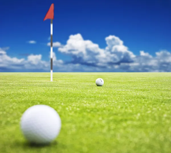 Мяч для гольфа на зеленом фоне с флагом - очень мелкая глубина резкости — стоковое фото