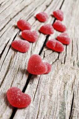 Red heart shaped jelly sweets on a rustic background clipart