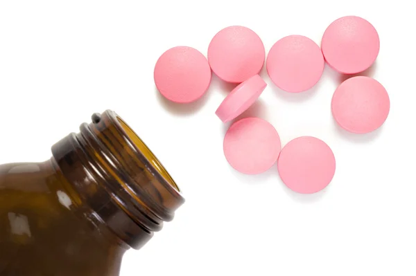 Рожева таблетка і пляшка таблеток на білому тлі з простором для тексту — стокове фото