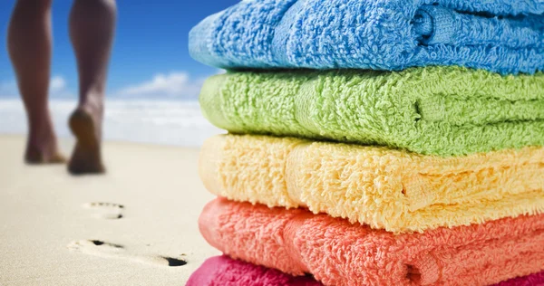 Kleurrijke handdoeken en iemand wandelen op het strand — Stockfoto