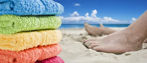 Toalhas coloridas e pés descalços na praia — Fotografia de Stock