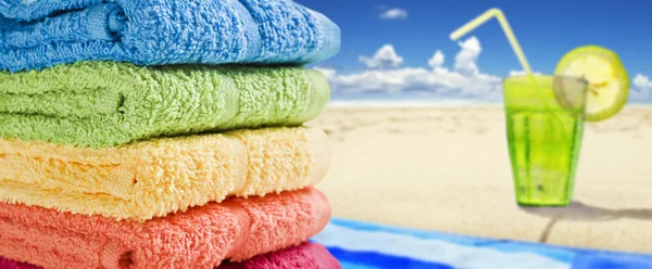 Kleurrijke handdoeken op een wit met een koud drankje — Stockfoto