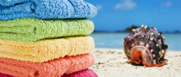 Bunte Handtücher an einem weißen Strand mit einer Muschel — Stockfoto