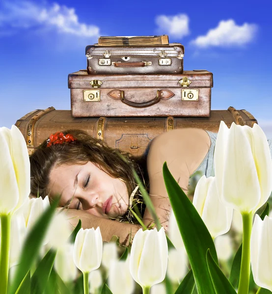 Mujer joven viajera descansando en un campo de tulipanes con sus maletas —  Fotos de Stock