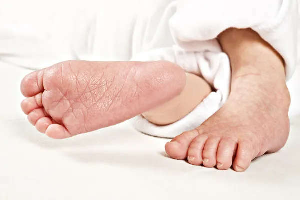 Beyaz üzerine yeni doğan bir bebeğin ayakları küçük — Stok fotoğraf