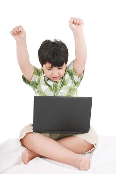 Ładny chłopczyk z laptopa w jego łóżku na biały — Zdjęcie stockowe