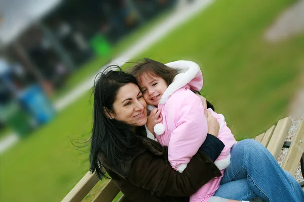 Diverse mom and daughter sitting in the bench — Stock Photo, Image