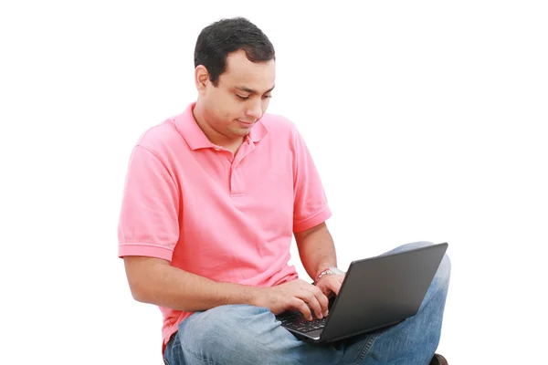 Молодой человек сидит на полу и работает с ноутбуком — стоковое фото