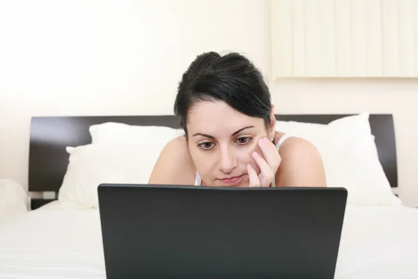 Krásná dívka relaxaci na lůžku s laptopem — Stock fotografie