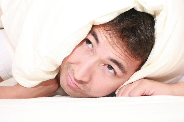 Homem tentando dormir com um travesseiro sobre a cabeça e perto de acordar — Fotografia de Stock