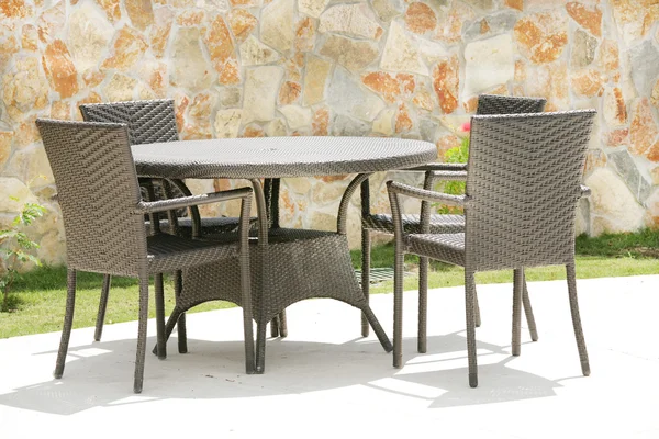Mesa y sillas en un jardín tropical con textura de pared de piedra — Foto de Stock