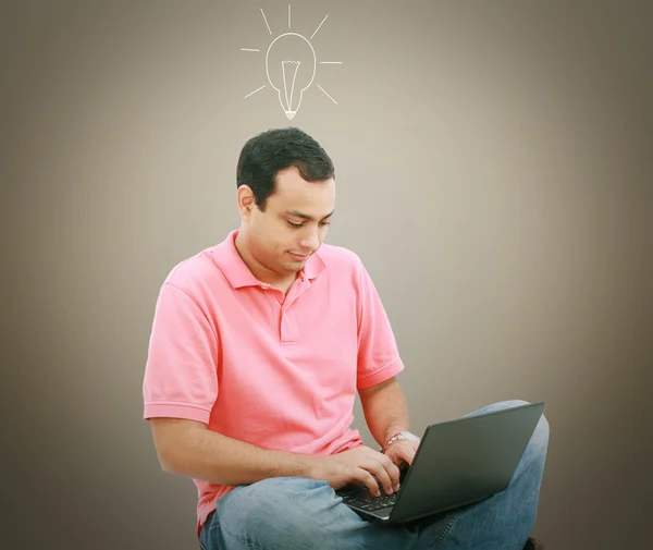 Homem usando um laptop com lâmpada sobre a cabeça — Fotografia de Stock